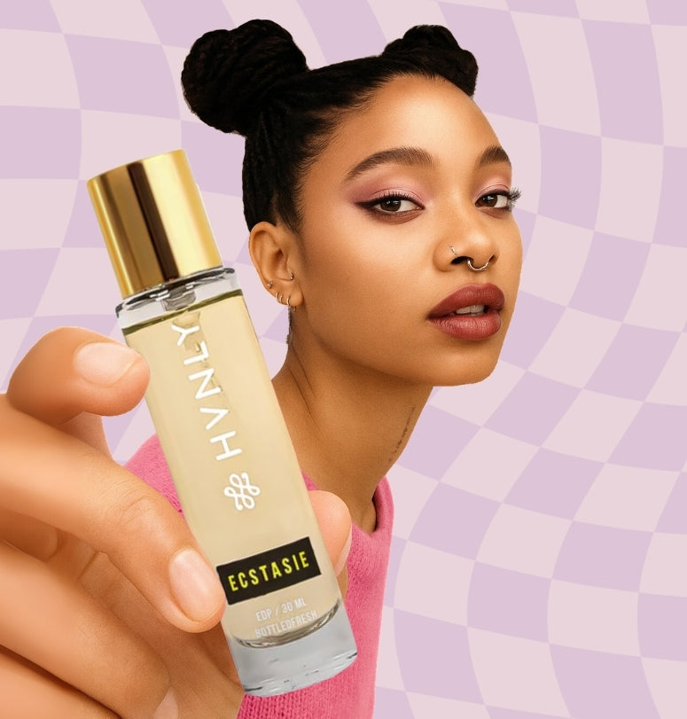 Woman holding a HVNLY's Ecstasie perfume bottle against a checkered background