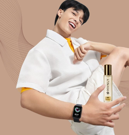 Person holding a bottle of HVNLY MAN perfume and a smartwatch on a beige background showing the size of the perfume bottle