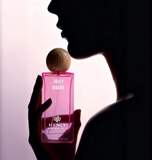 Shadow body shot of a person holding a pink 'Juicy Rouge' perfume bottle with 'HVNLY' branding