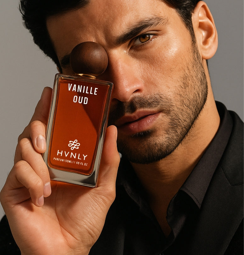 Man holding a Vanille Oud perfume bottle by HVNLY close to his face against a neutral background