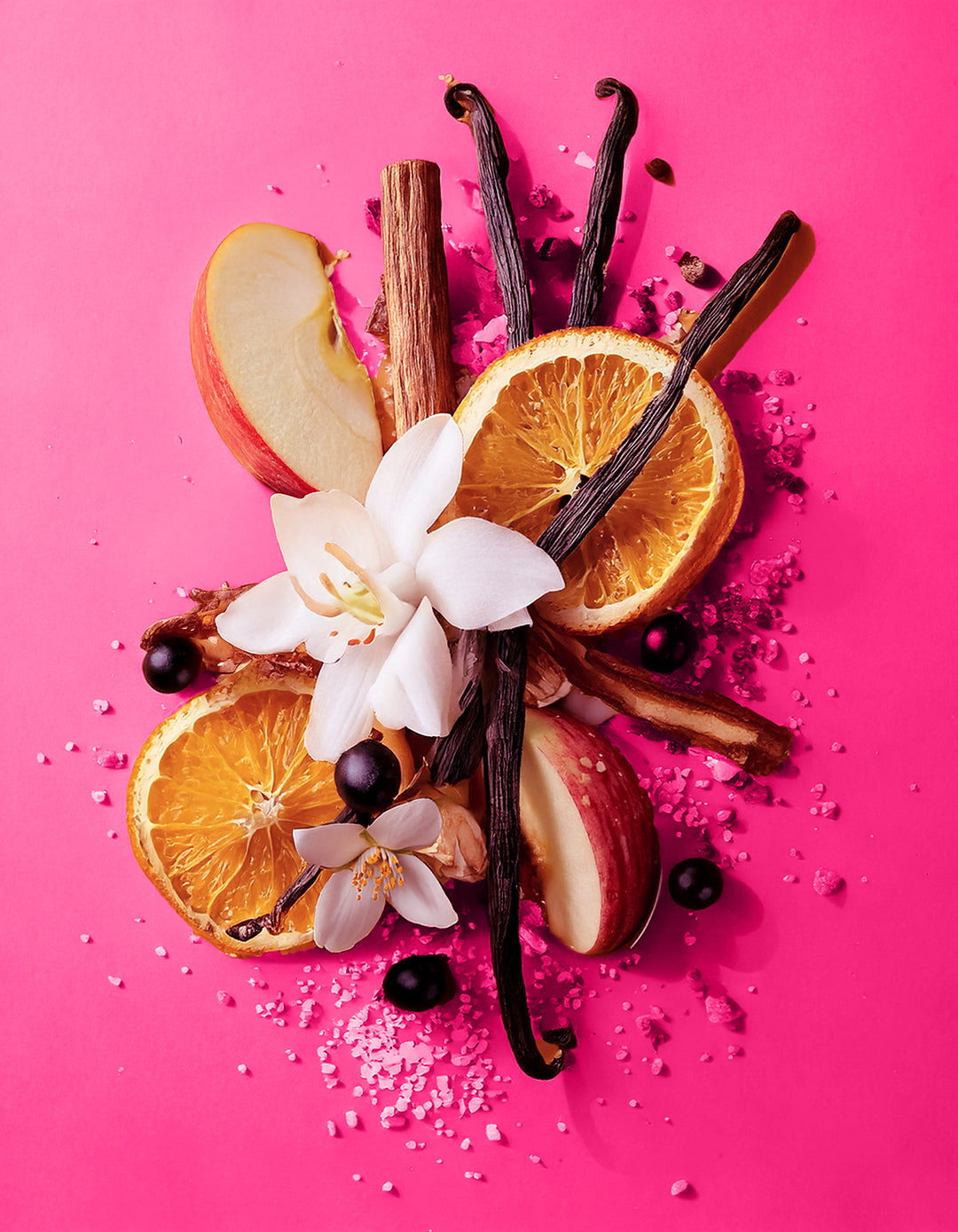 Spices and fruits arranged on a pink background. Colorful display of natural ingredients used in HVNLY Floral Crush luxury perfume