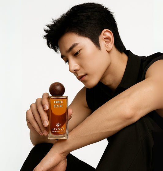 Person holding a perfume bottle labeled 'Amber Desire' by Hvnly on a white background