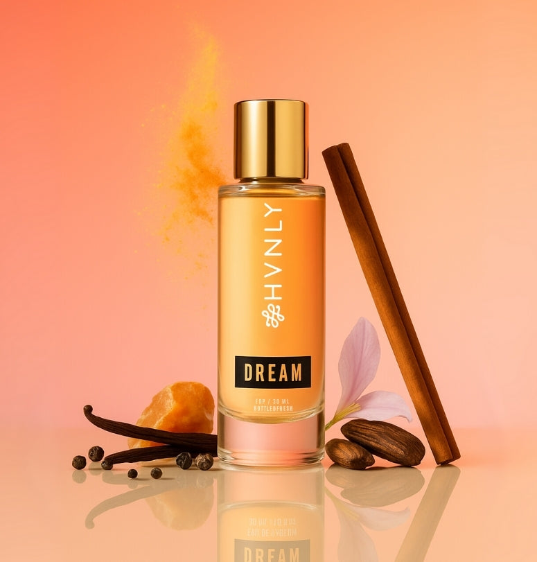Perfume bottle 'Dream' by HVNLY with cinnamon stick, vanilla bean, and orange on a peach background