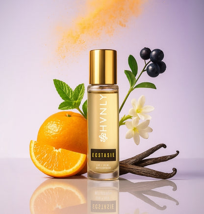 Perfume bottle labeled Ecstasie with an orange, vanilla bean, and flowers on a reflective surface showcasing the colourful imagery of the ingredients
