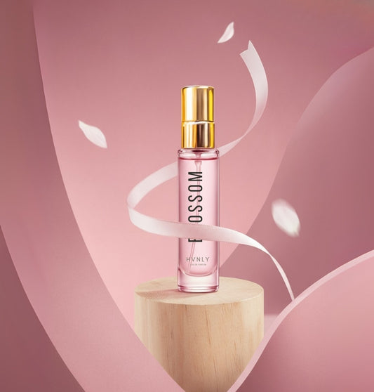 HVNLY's Blossom Perfume bottle with gold cap on a wooden platform against a pink background