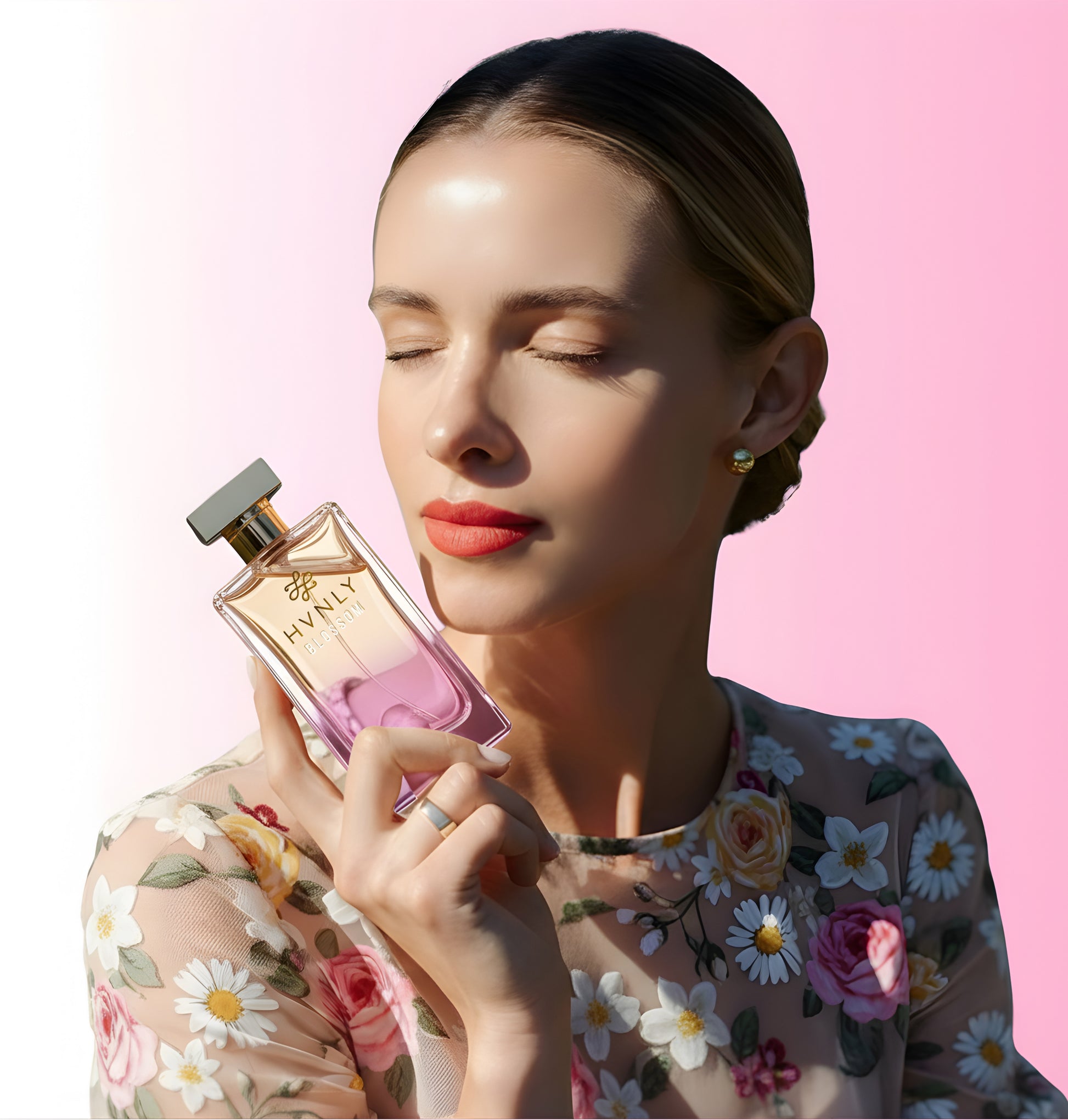 Woman holding HVNLY's Blossom perfume bottle with a pink background