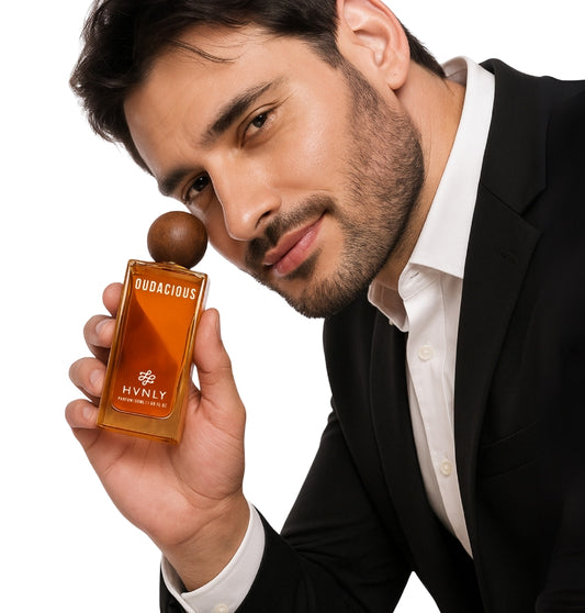 Man holding a perfume bottle labeled 'Oudacious' by Hvnly against a white background showcasing the sleek design and dimensions of the perfume.