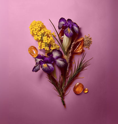 Arrangement of purple and yellow flowers with amber stones on a pink background Colorful display of natural ingredients used in HVNLY Velvet Blush luxury perfume

