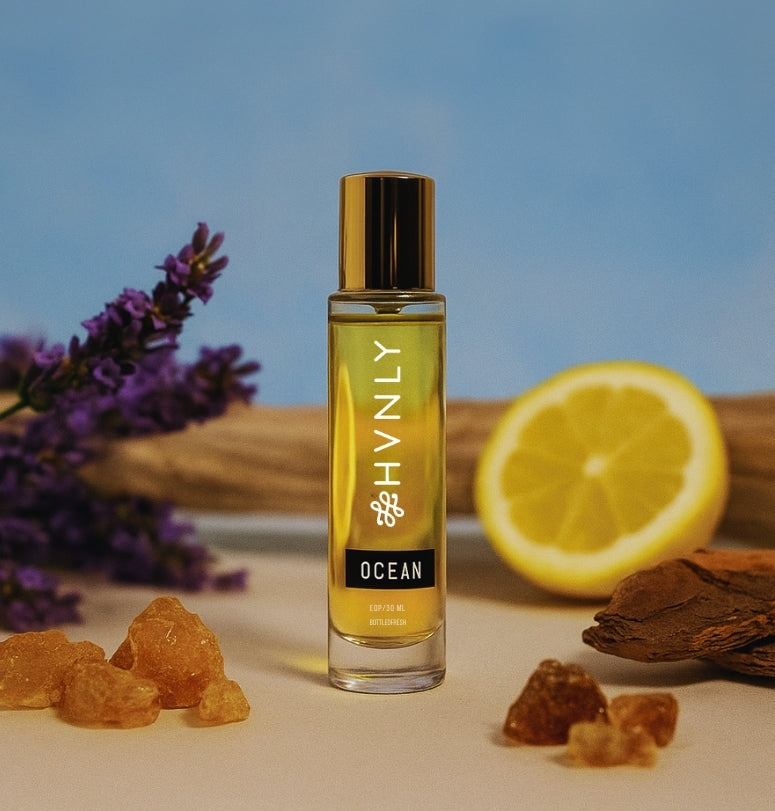 Perfume bottle labeled 'HVNLY Ocean' with lavender, lemon, and frankincense on a blue background showcasing the colorful ingredients of the perfume.