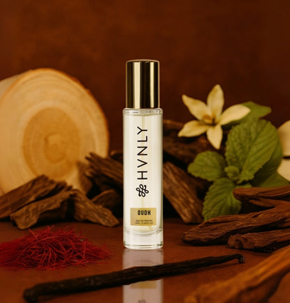 Small bottle labeled 'HVNLY Oudh' with vanilla beans and flowers on a wooden surface showing notes of the perfume