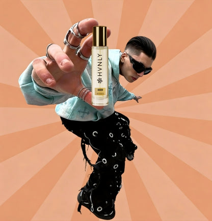 Person holding a bottle of HVNLY Oudh perfume against an orange radial background showcasing its handy size