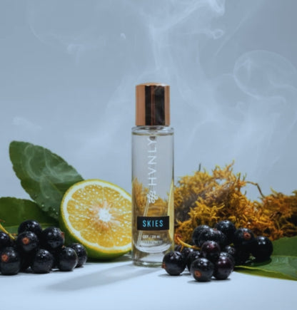 Skies perfume bottle with orange, black currants, and leaves on a light gray background
