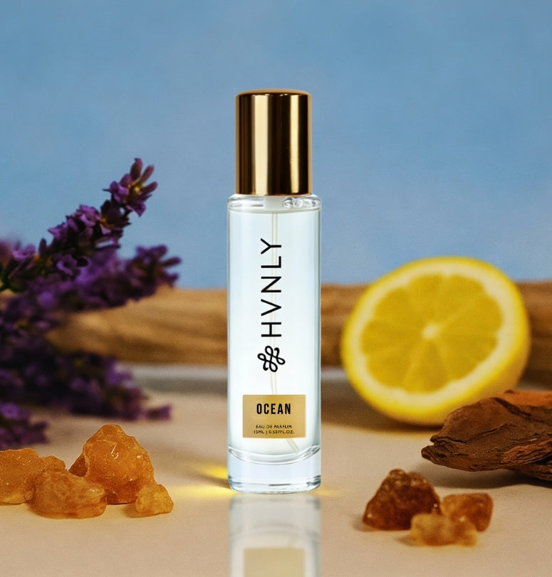Perfume bottle labeled 'HVNLY' with ocean perfume, surrounded by lavender, lemon, and amber gummy candies on a blue background showing the notes of the perfume.