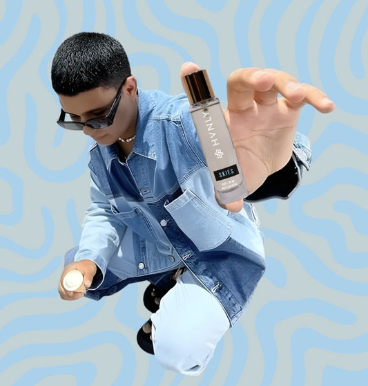 Person holding the perfume bottle with a blue and gray patterned background showcasing its sleek and elegant design 