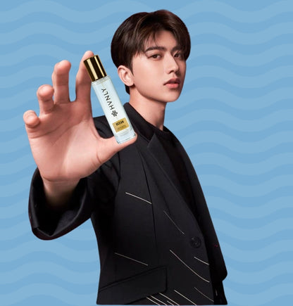 Person holding a bottle of 'HVNLY Ocean' perfume against a blue background showcasing its handy size