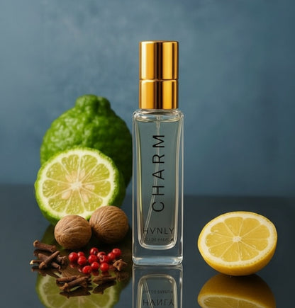Perfume bottle labeled 'CHARM' with fruits and spices on a reflective surface depicting ingredients