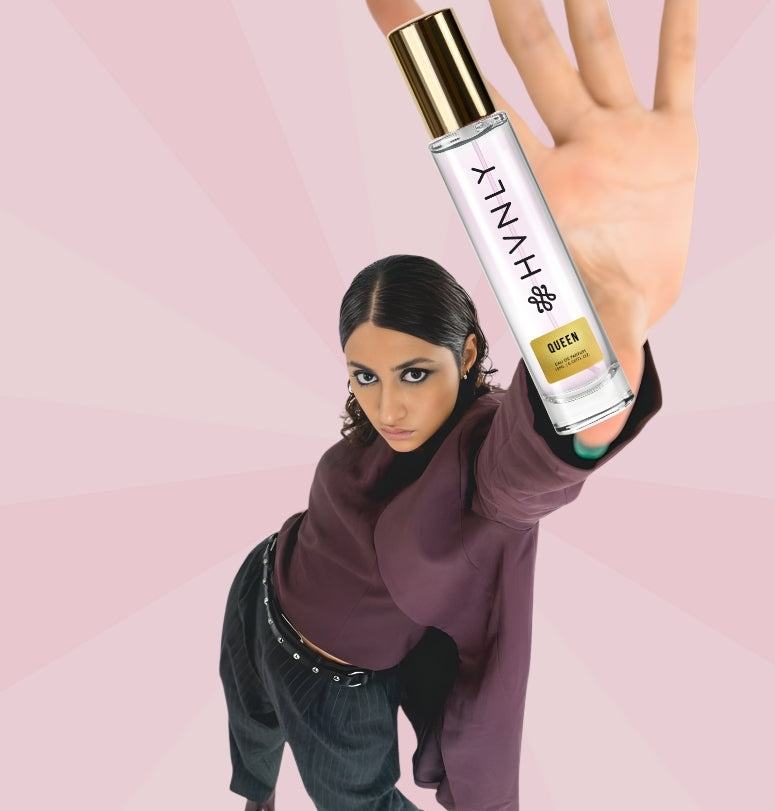 Person holding a HVNLY Queen perfume bottle against a pink background showing its handy size