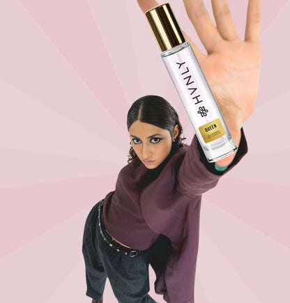 Person holding a HVNLY Queen perfume bottle against a pink background showing its handy size