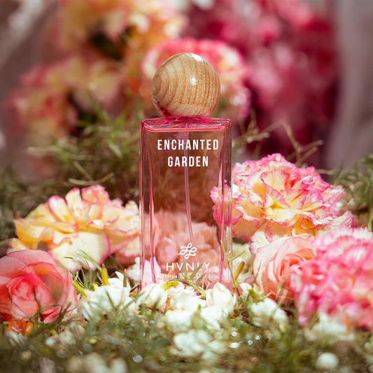 Perfume bottle labeled 'Enchanted Garden' by Hvnly surrounded by flowers showcasing a sensorial feeling that the users experience.