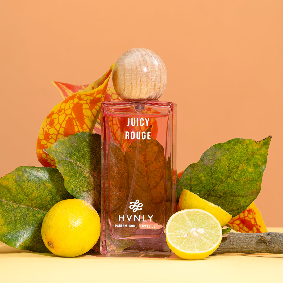 Hvnly Juicy Rouge perfume bottle with lemons and leaves on a peach background