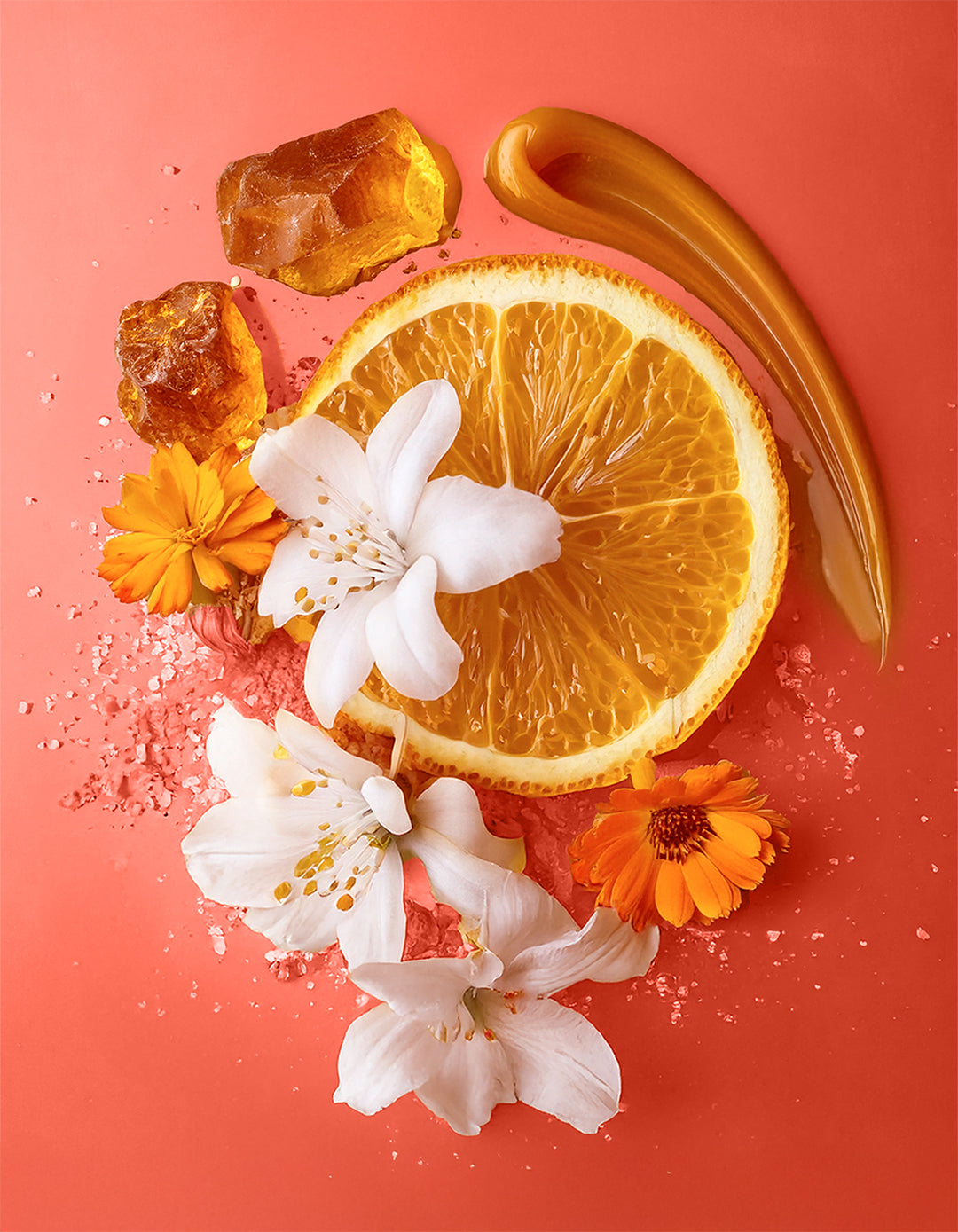 Sliced orange with flowers and crystals on a pink background. Colorful display of natural ingredients used in HVNLY Enchanted Garden luxury perfume

